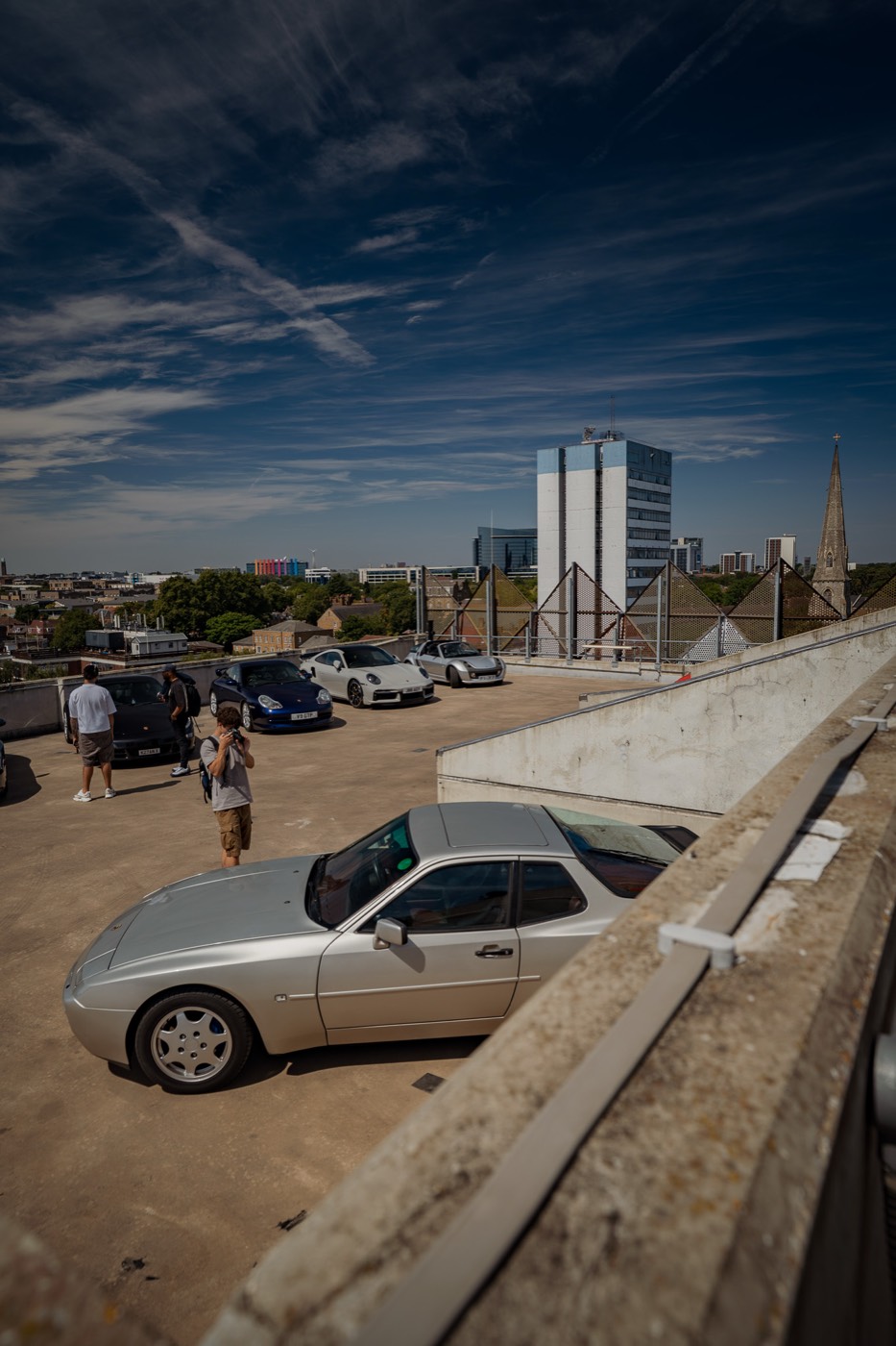 Rooftop car park with a line of Porsches and a view over West London