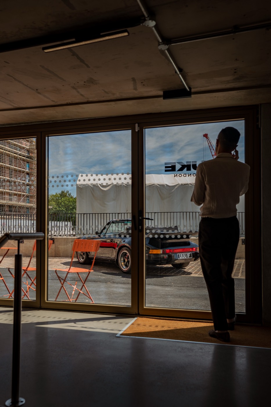 Duke of London entrance with a Porsche 911 reflected in the glass doors
